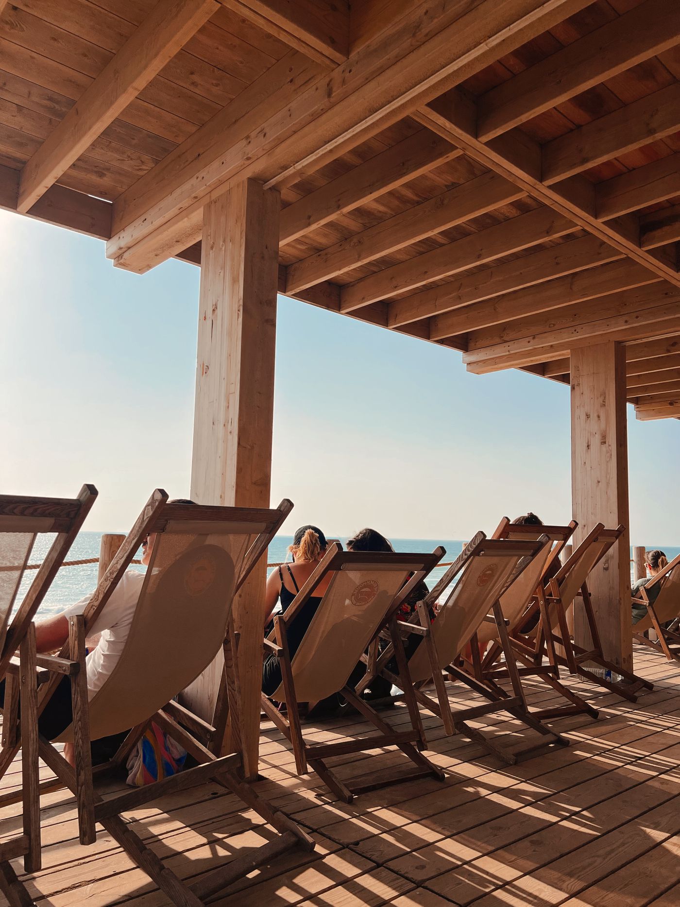 Sunlit coastal timber deck with substantial exposed beams