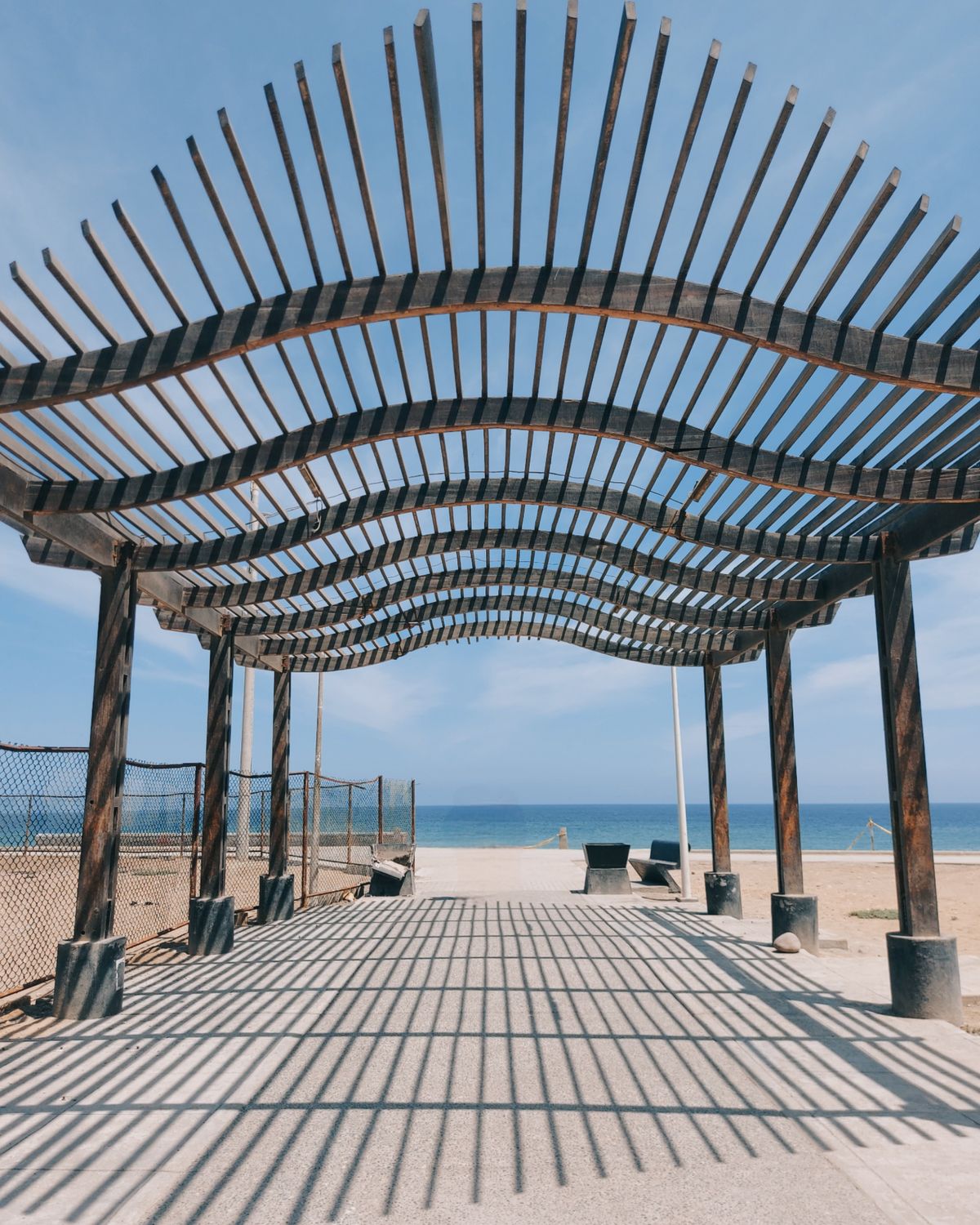 Beachside timber pergola with ocean views and summer shadows